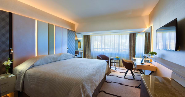 Four Seasons Hotel twin room with blinds closed, desk, coffee table and nightstands.